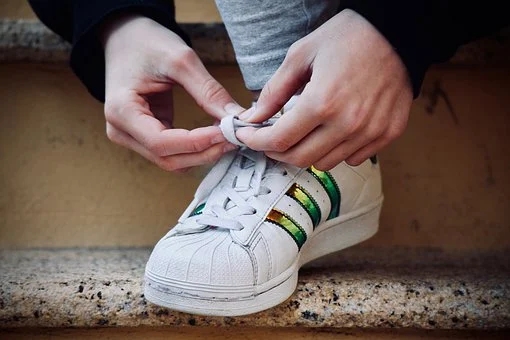Ein paar Hände schnürt den Sportschuh. Gleich geht es los. 